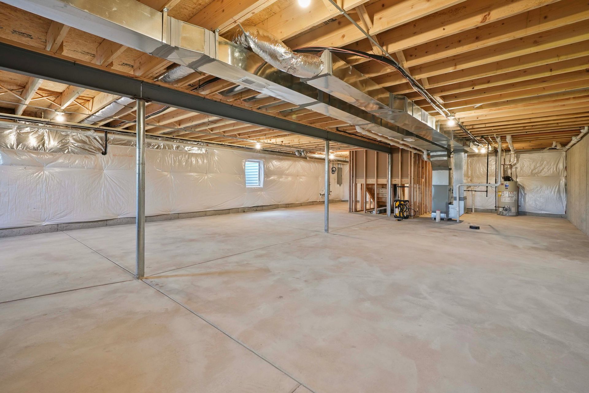 Empty unfinished basement with exposed wooden beams, ductwork, and concrete floor