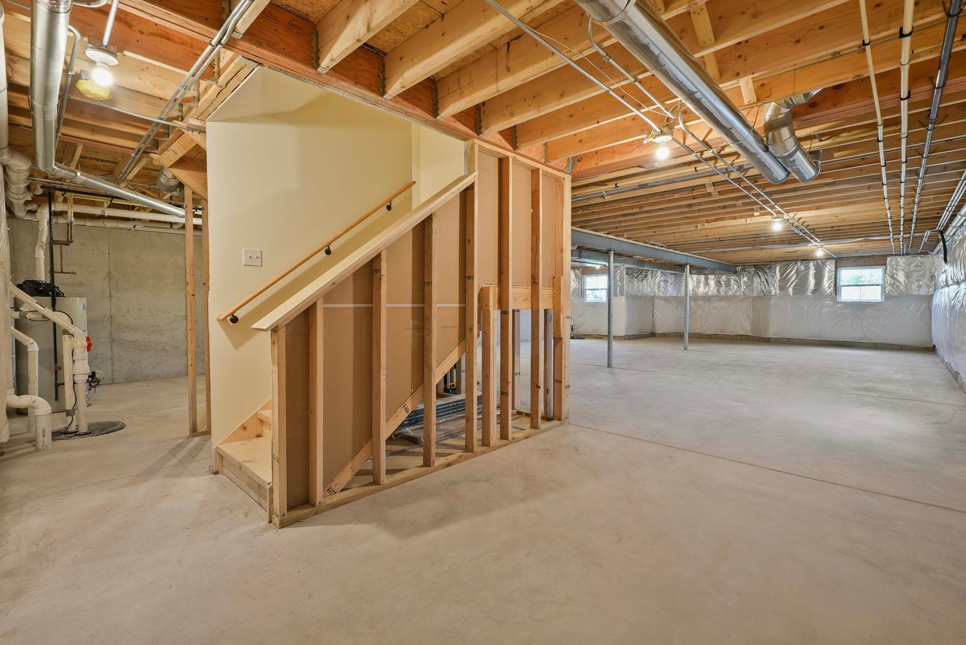 Unfinished basement with wooden stair framing, exposed beams, and concrete floor