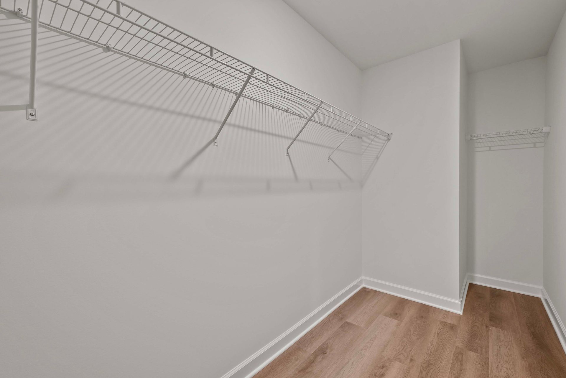 Empty walk-in closet with wire shelves and wood flooring