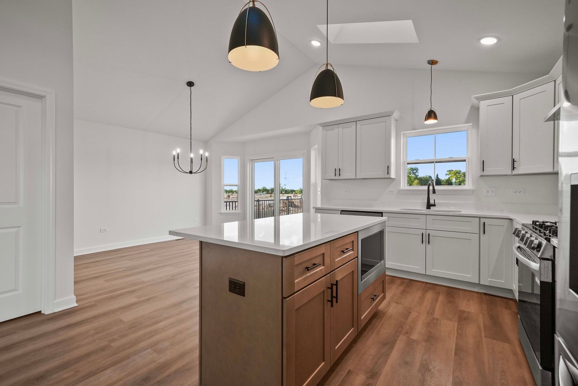 Bright modern kitchen with white cabinets, wood island, pendant lights, and hardwood floors