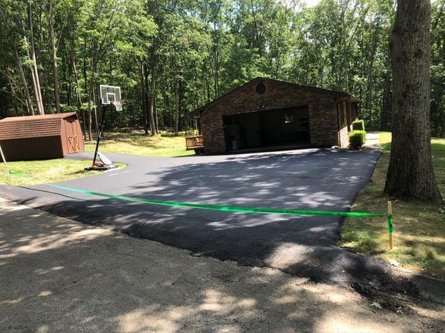 There is a basketball hoop in the middle of the driveway.