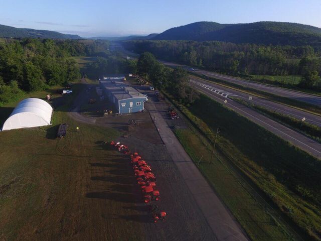 An aerial view of a farm with a highway and mountains in the background.