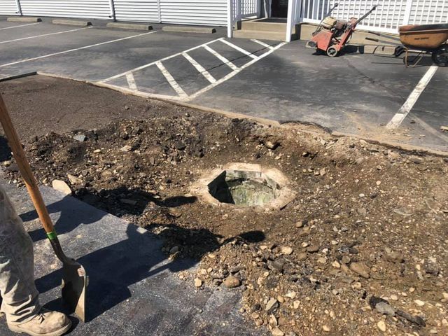 A person is digging a hole in the ground in a parking lot.