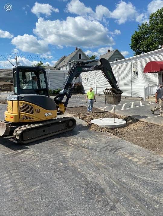 A man is standing next to a bulldozer in a parking lot.