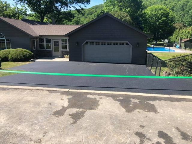 A house with a garage and a green ribbon in front of it.