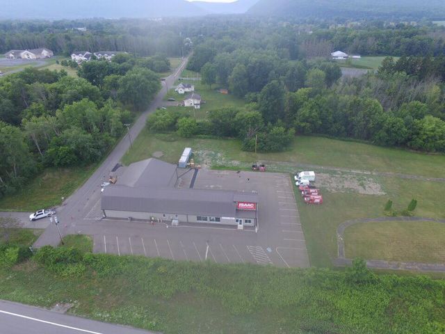 An aerial view of a large building surrounded by trees and a road.