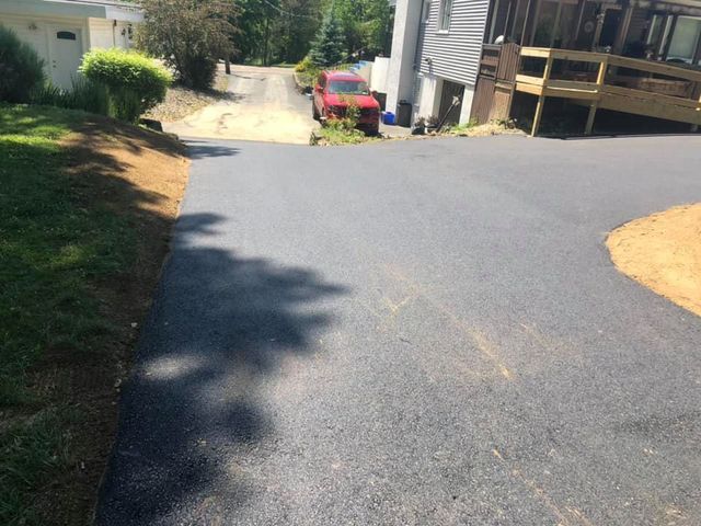 A red truck is parked in a driveway next to a house.