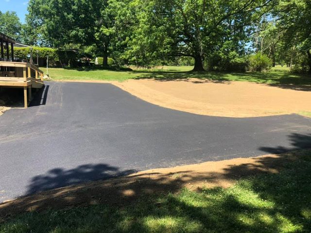 A driveway with a deck and trees in the background.