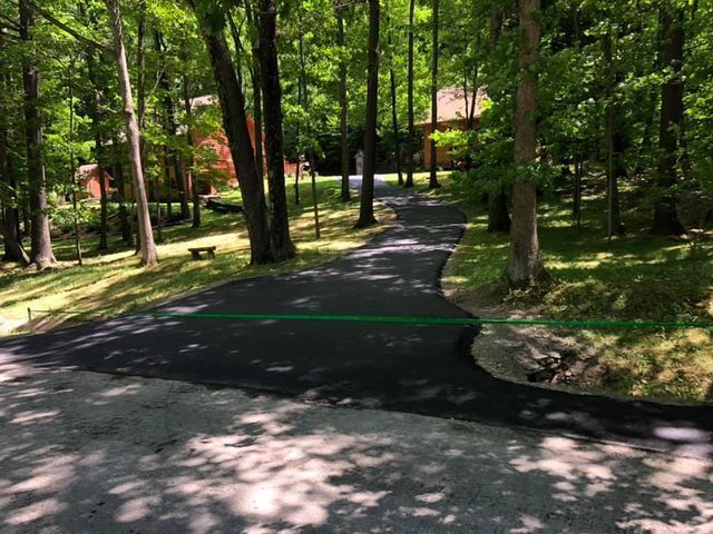 A driveway leading to a house in the woods.