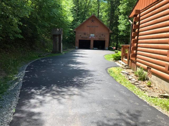 A driveway leading to a log cabin in the woods
