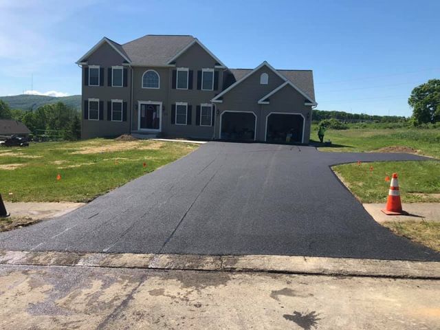 A large house with a newly paved driveway in front of it.