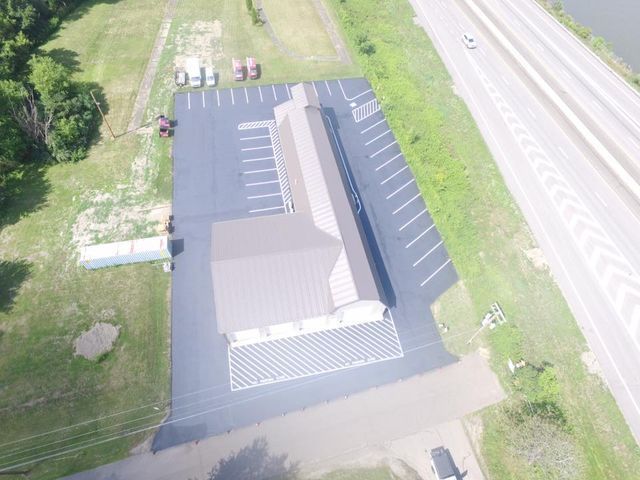 An aerial view of a building and parking lot next to a highway.