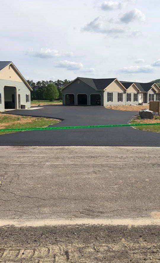 A large house is being built next to a large asphalt driveway.
