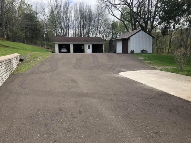 A driveway leading to a garage with a car parked in it.