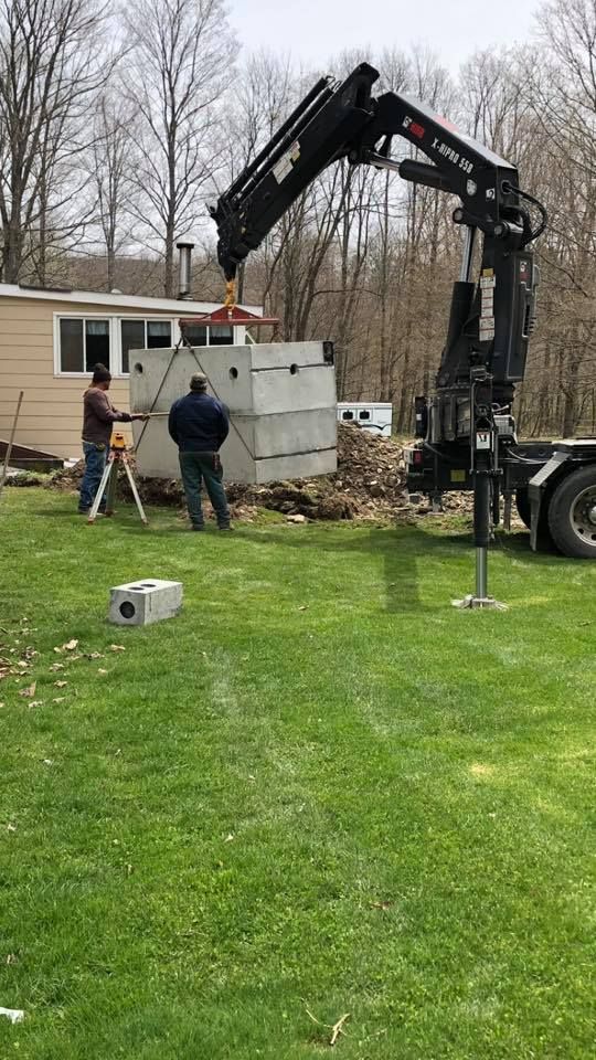 A crane is lifting a concrete box in a yard.