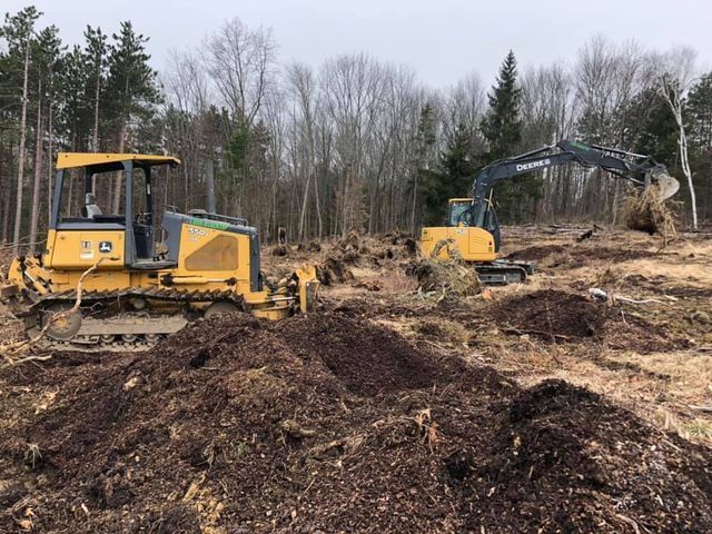 A bulldozer and an excavator are working in a field.