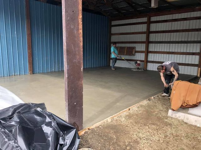 Two men are working on a concrete floor in a garage.