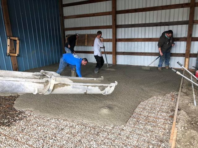 A group of people are working on a concrete floor in a building.