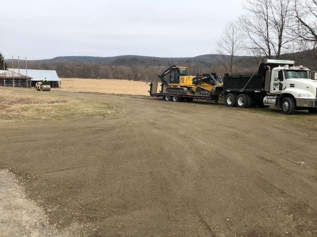 A dump truck is carrying a bulldozer on a trailer.