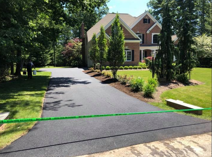 A large brick house with a black driveway leading to it