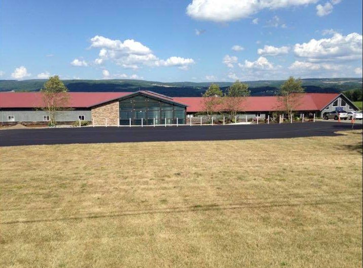 A large building with a red roof sits in the middle of a field