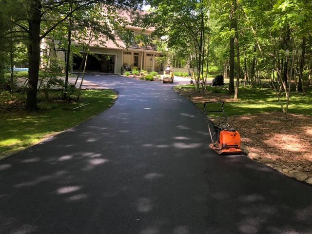 A lawn mower is sitting on the side of a driveway next to a house.