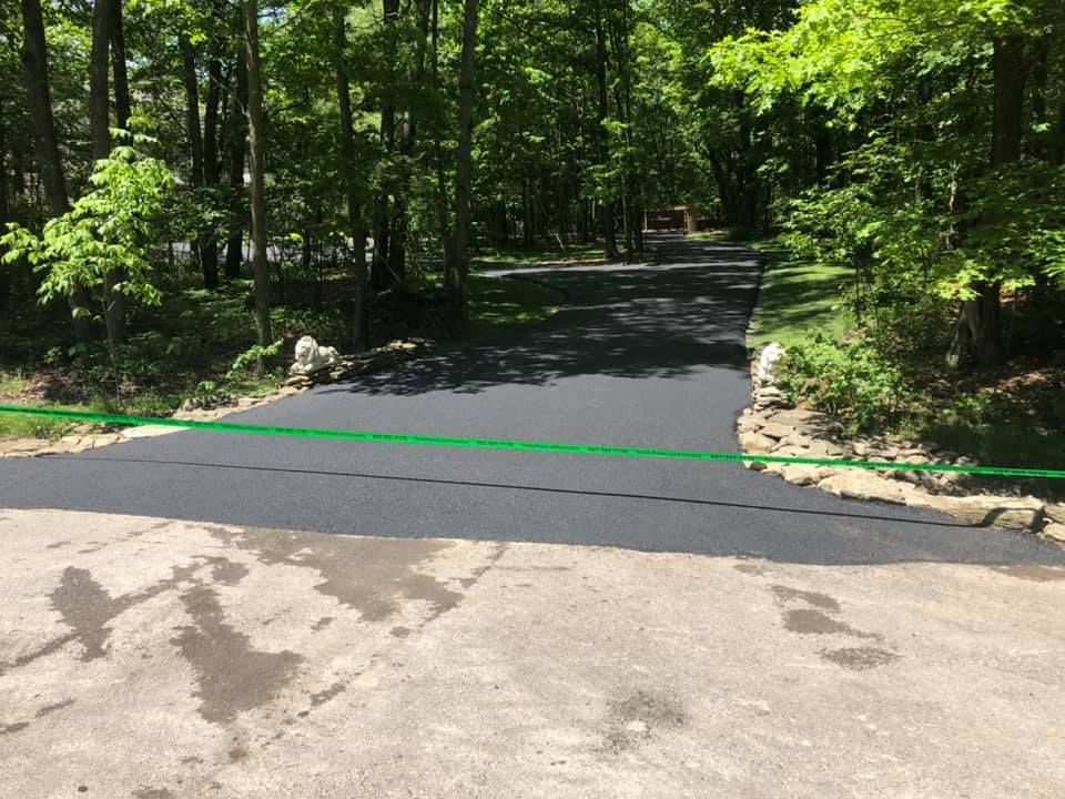 A black asphalt road with a green hose on the side of it.