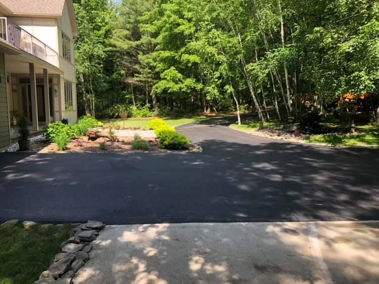 A driveway leading to a house with trees in the background.