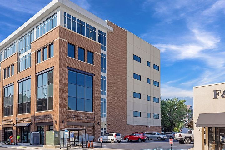 A large brick building with a lot of windows is next to a smaller building.