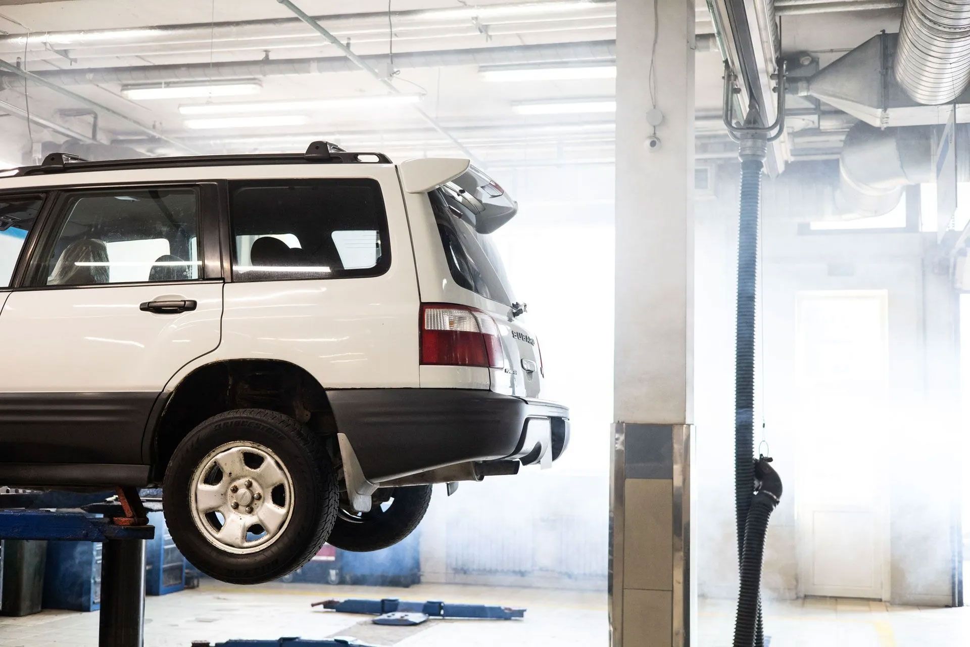 White SUV on a lift in a smoky auto repair garage