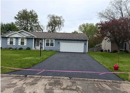 Single-story blue house with a driveway, lawn, and garage on a cloudy day