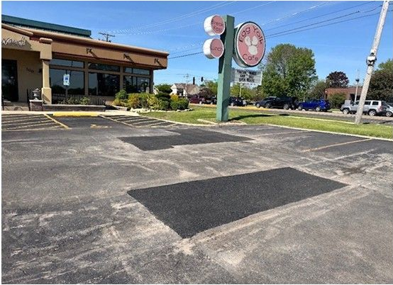Parking lot and storefront with large red signs on a sunny day