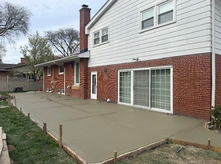 Concrete patio beside a white-and-red brick house with sliding glass doors and a side entrance.