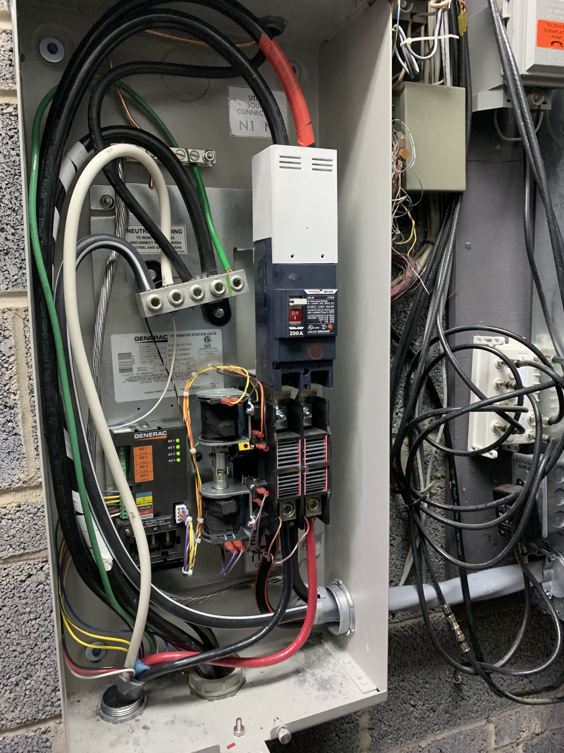 Electrical panel with wires, breakers, and components in a factory setting.