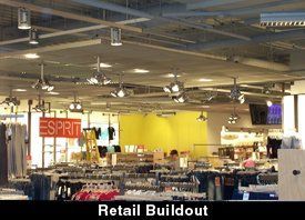 Retail store interior with clothing racks, signage, and overhead lighting.