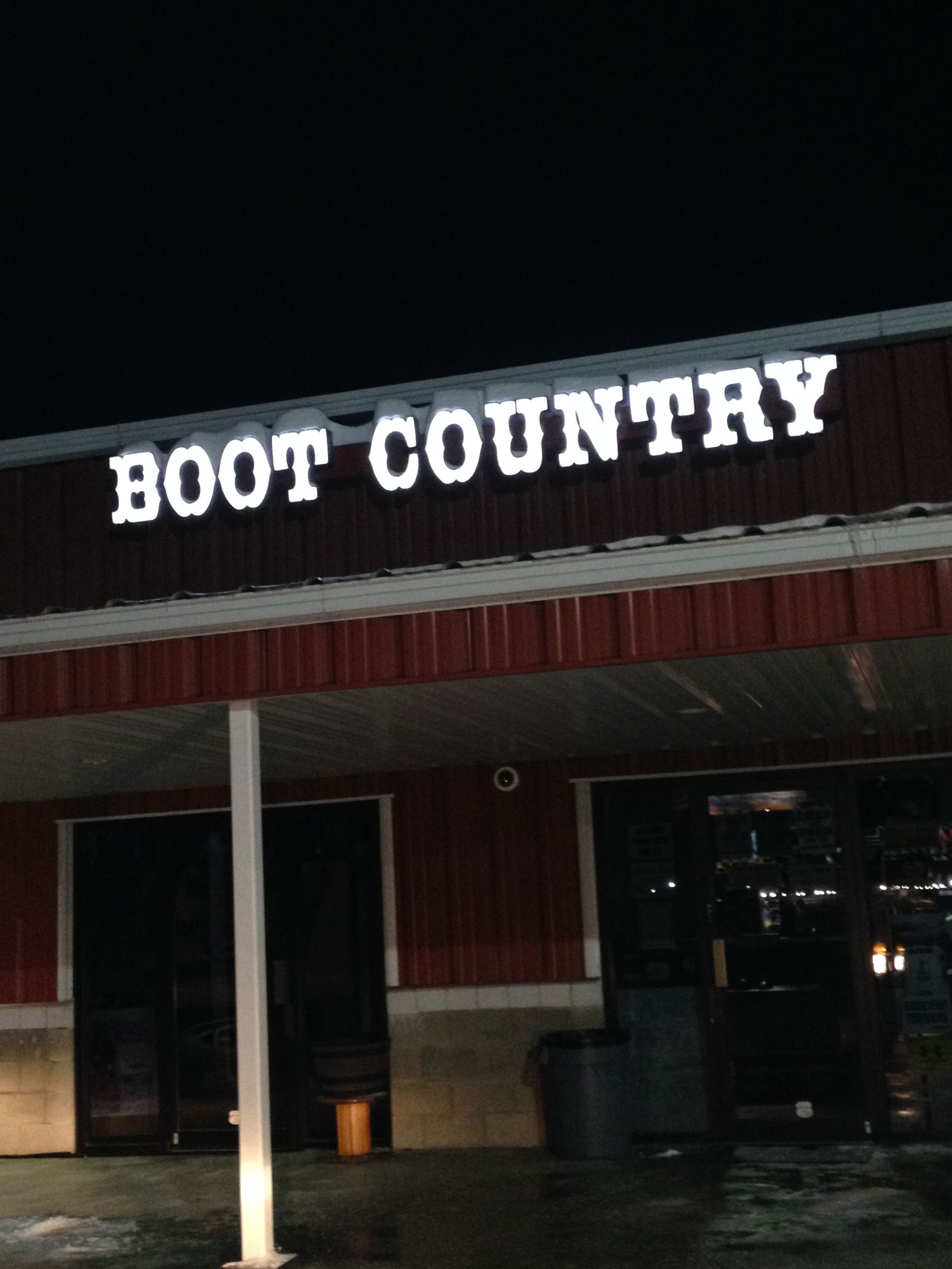 Boot Country store sign at night. White illuminated letters on red building.