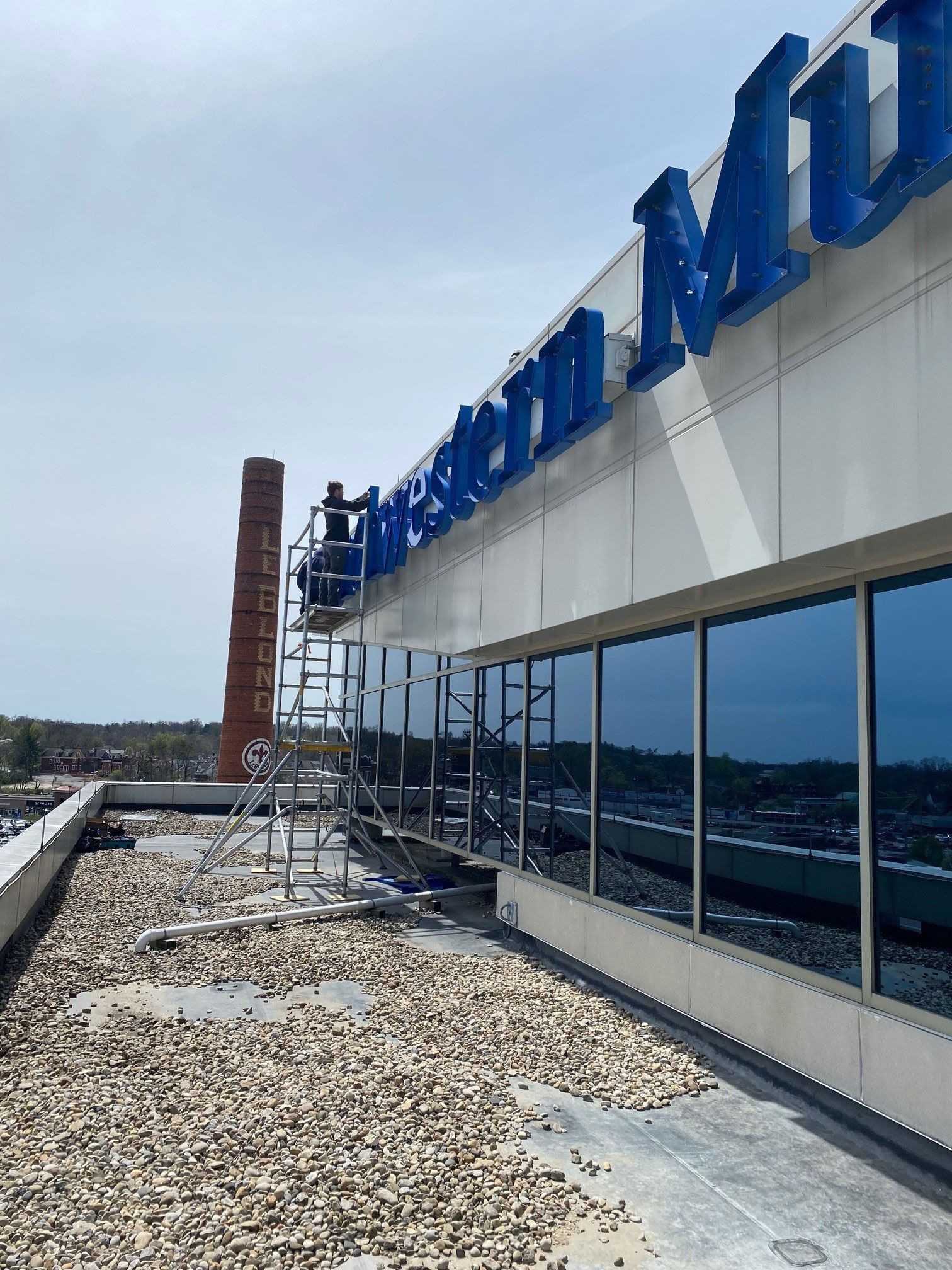 Workers on scaffolding near a building's blue signage, 