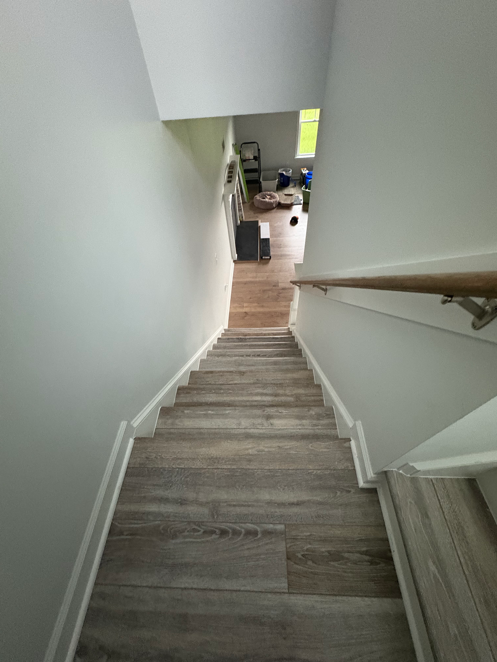 Hallway with hardwood floors, white trim, and light gray walls leading to a door.