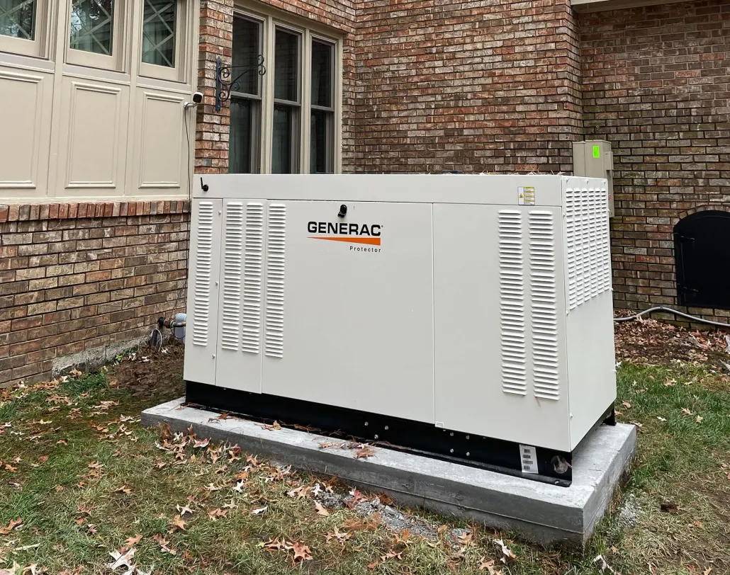 White generator or HVAC unit on a concrete pad beside a brick building in a grassy yard