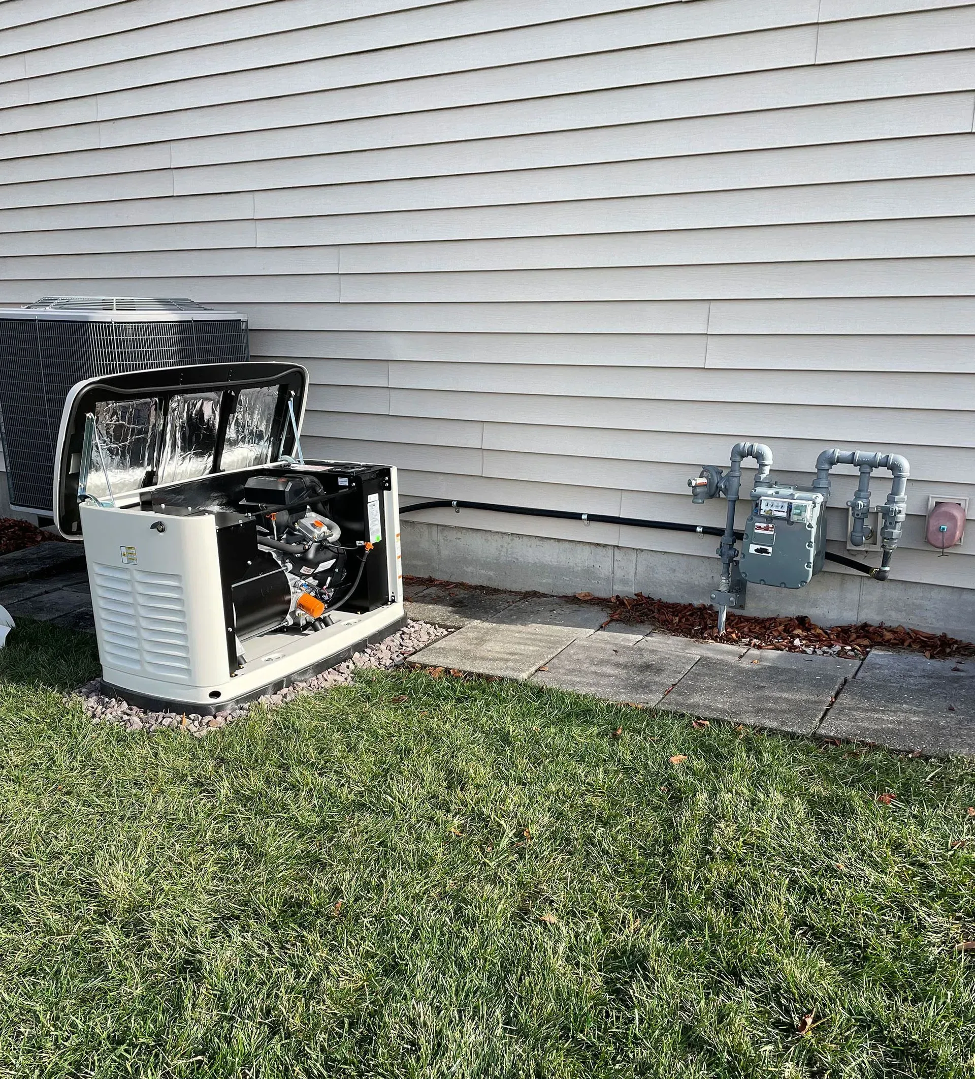 Outdoor HVAC unit beside a house with utility meters and white siding, sitting on a grassy lawn
