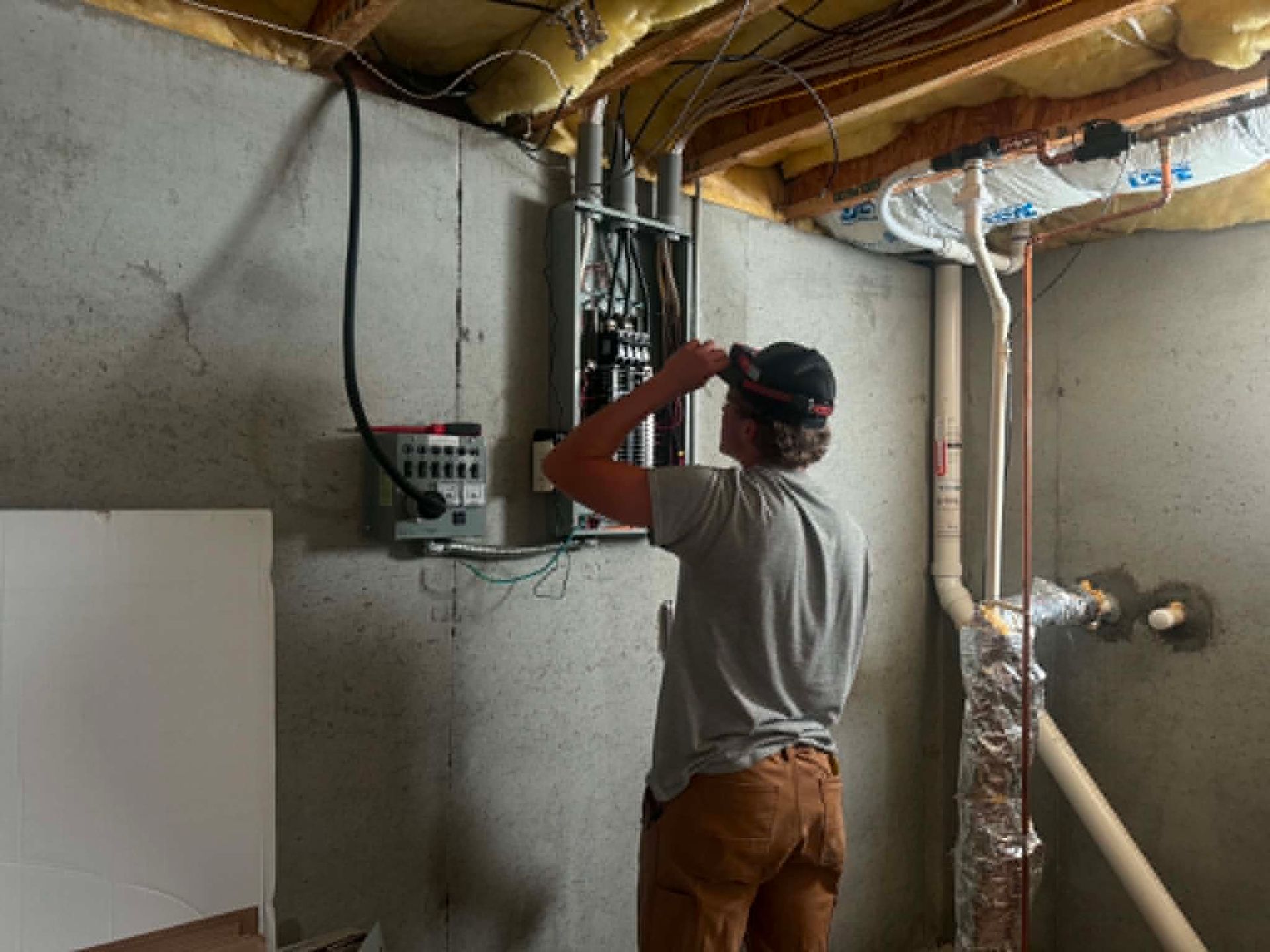 Person using a power tool near exposed ceiling joists in an unfinished basement