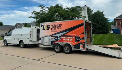 White truck and orange enclosed trailer parked on a residential street with ramp extended.