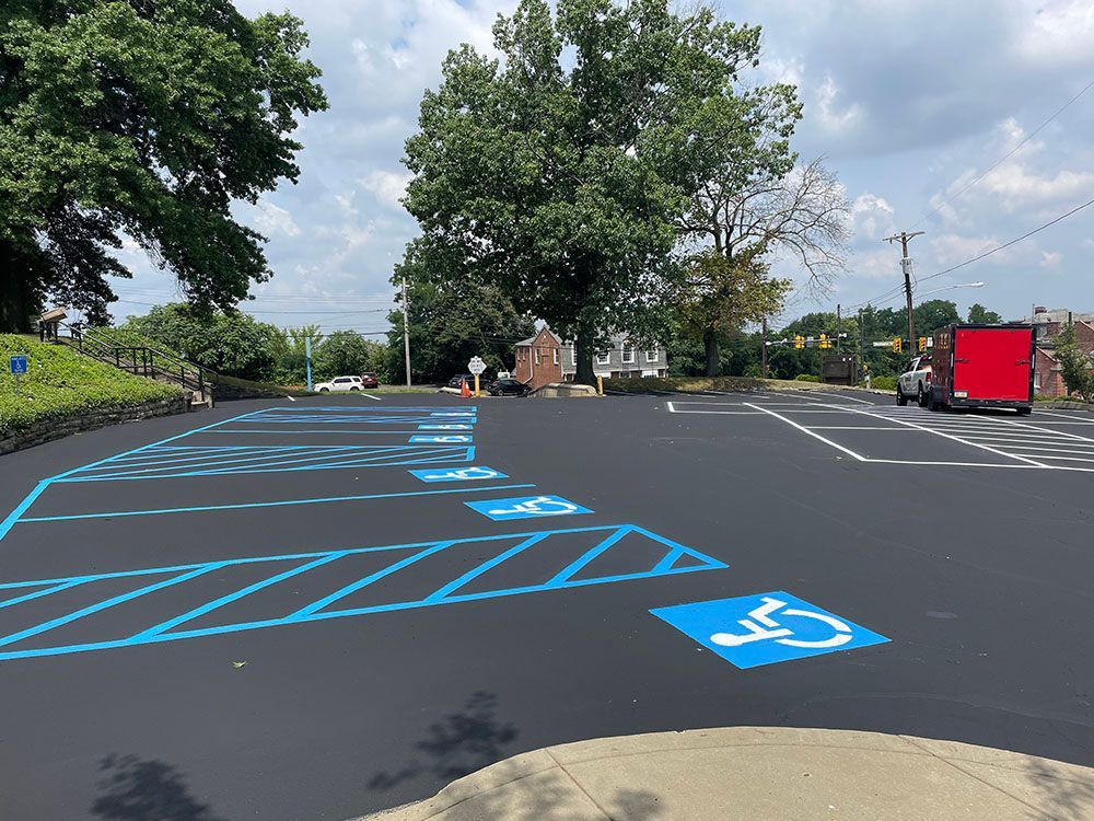Newly paved asphalt parking lot with blue handicap parking spaces.