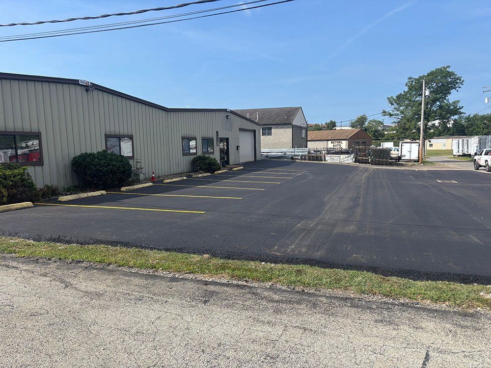 Exterior of a commercial building with asphalt parking lot under a blue sky.