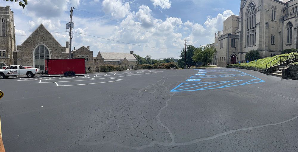 Parking lot with faded blue handicap parking spots, church buildings, and a cloudy sky.