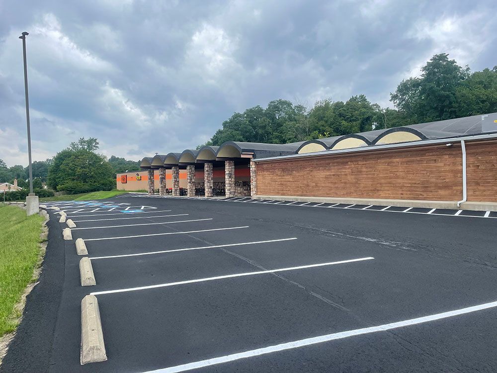 Newly paved parking lot in front of a brick building with a curved roof. Overcast day.