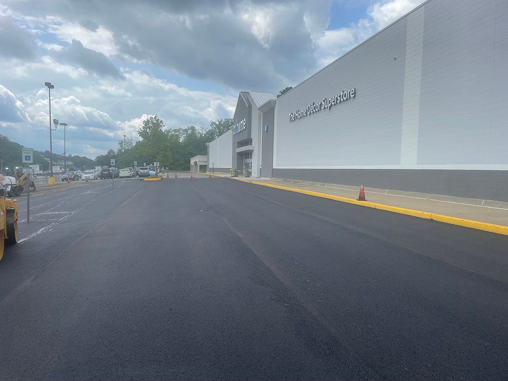 Paved parking lot in front of a white building with the name 