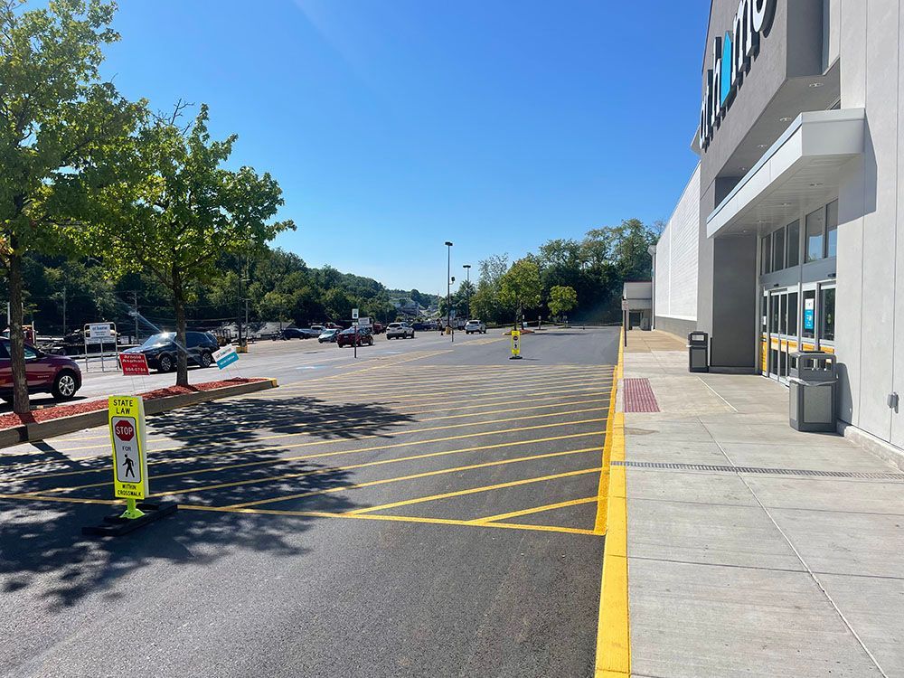 Exterior of store, wide view of parking lot on sunny day; stop sign in foreground.