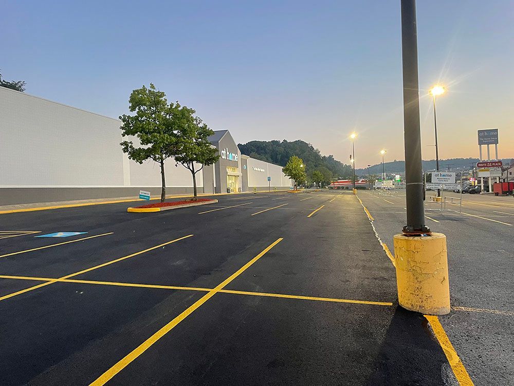 Empty parking lot in front of a Walmart store. Trees and streetlights. Mountains in the background. Blue sky.