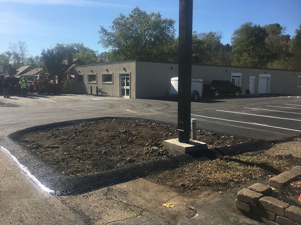 Newly paved parking lot with a planted island, building in the background.
